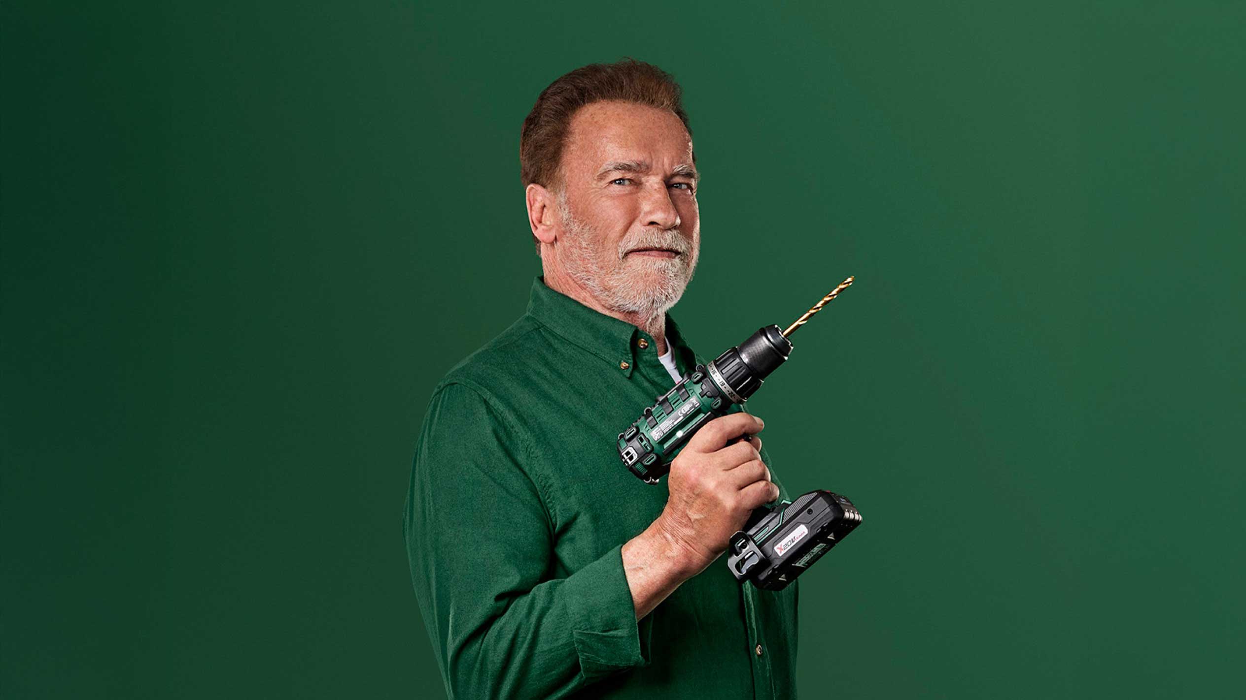 Arnold Schwarzenegger drži zeleni akumulatorski vrtalnik z baterijo X20V.