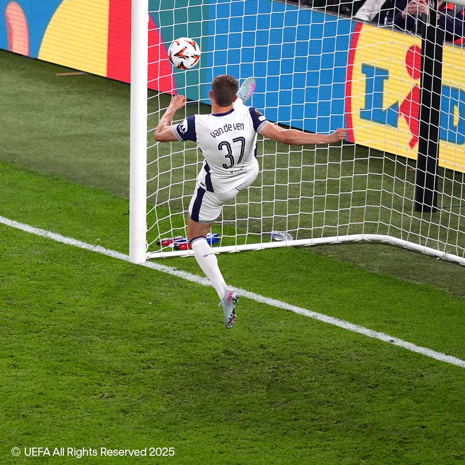 Nogometaš v belem dresu s številko 37 brca žogo v gol.