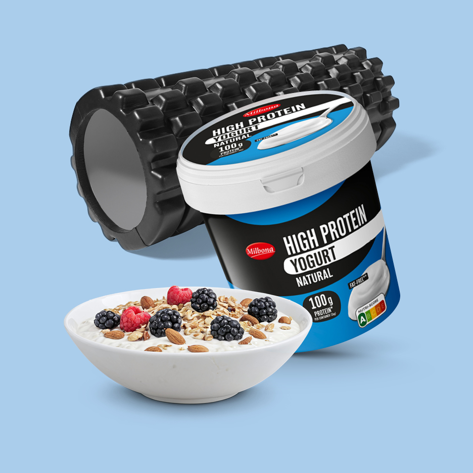 Visokobeljakovinski jogurt s skledo kosmičev in masažnim valjem v ozadju.