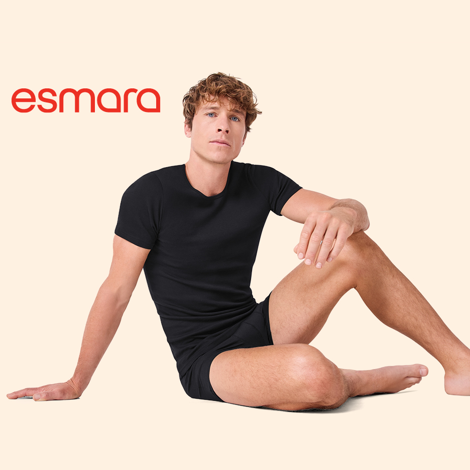 Moški v črni majici in boksaricah sedi na tleh.