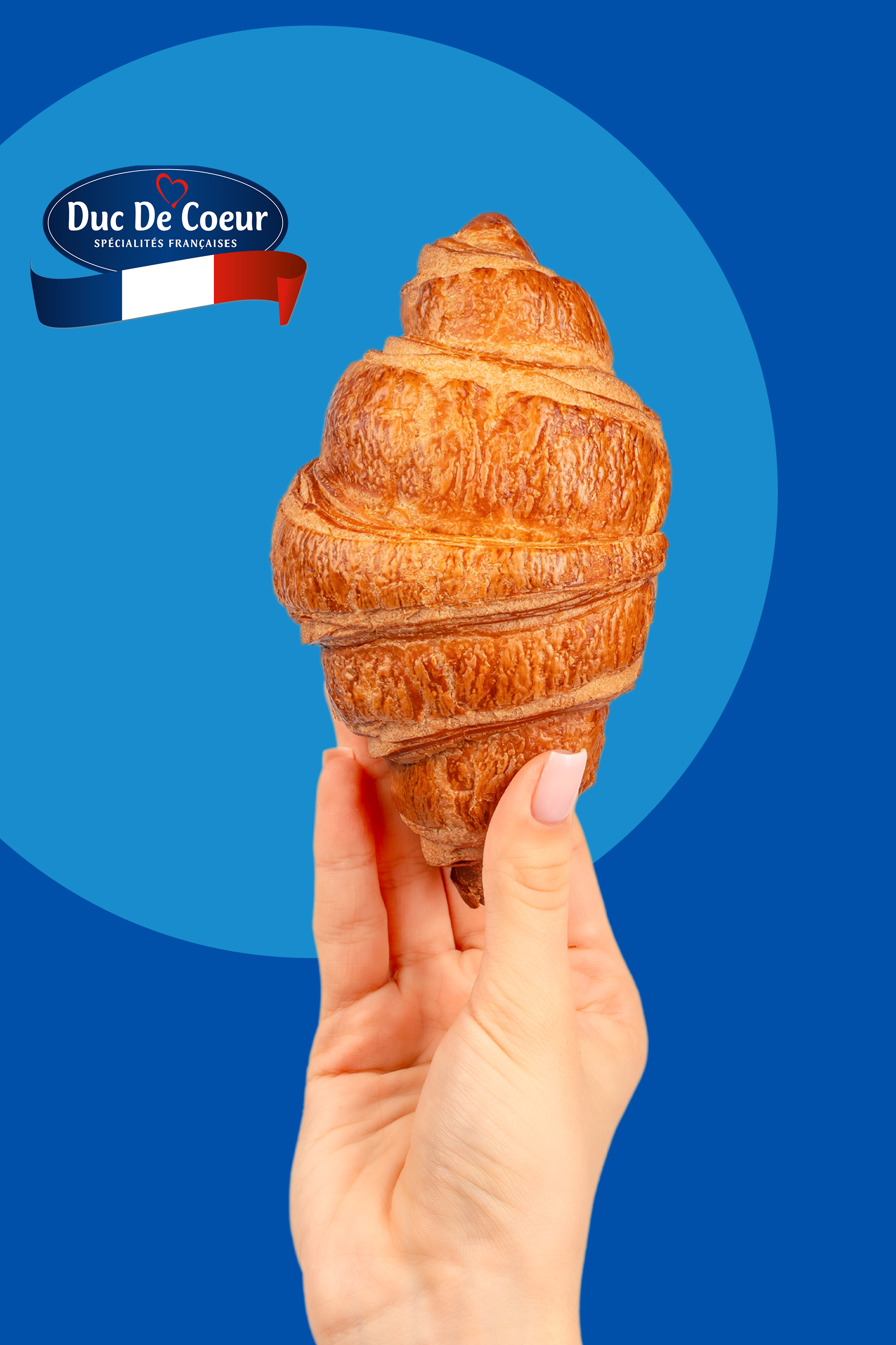 Roka drži zlato zapečen rogljiček na modrem ozadju z logotipom francoskih specialitet.