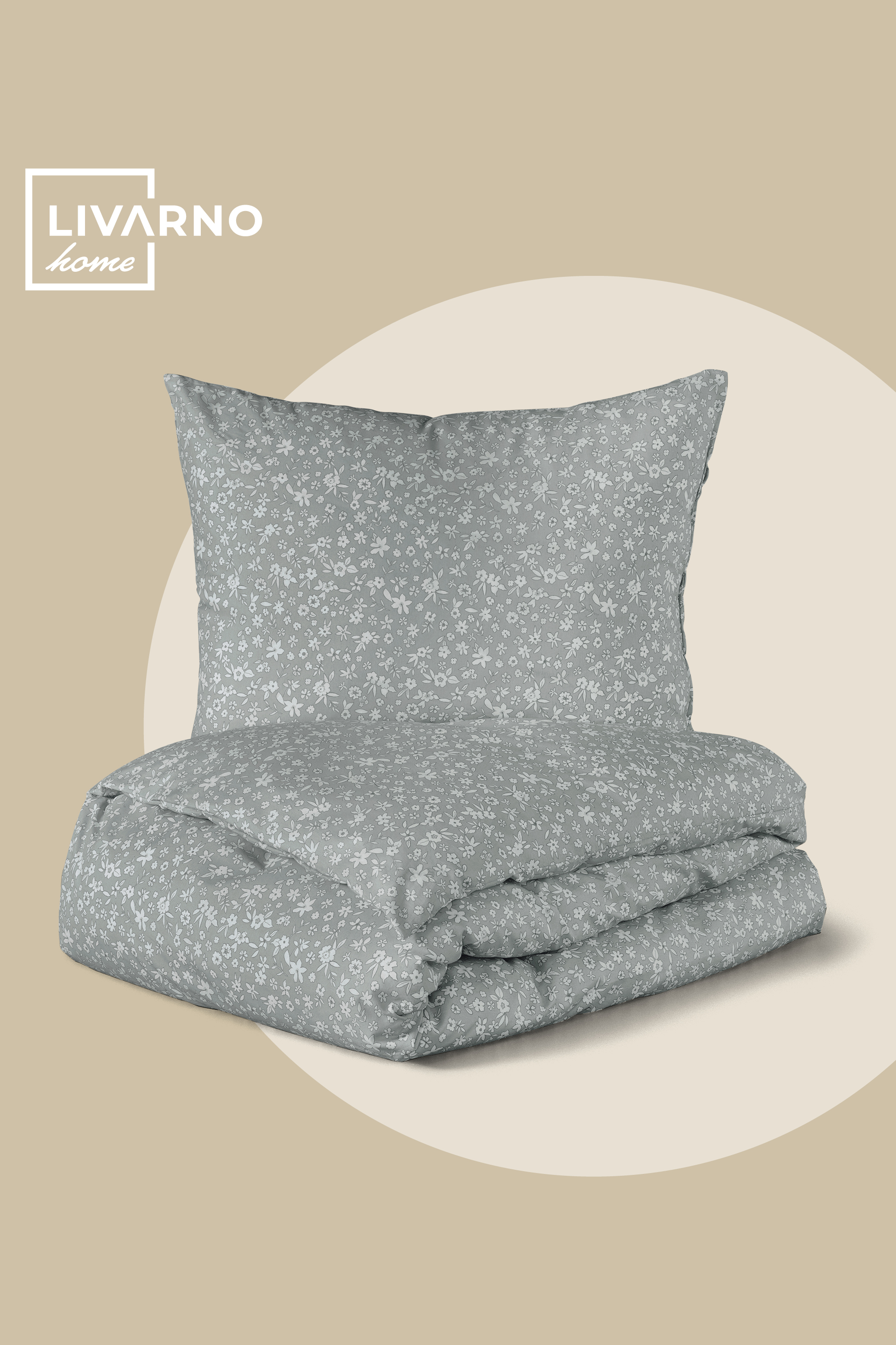 Svetlo siva posteljnina z belim cvetličnim vzorcem, zložena na bež ozadju.