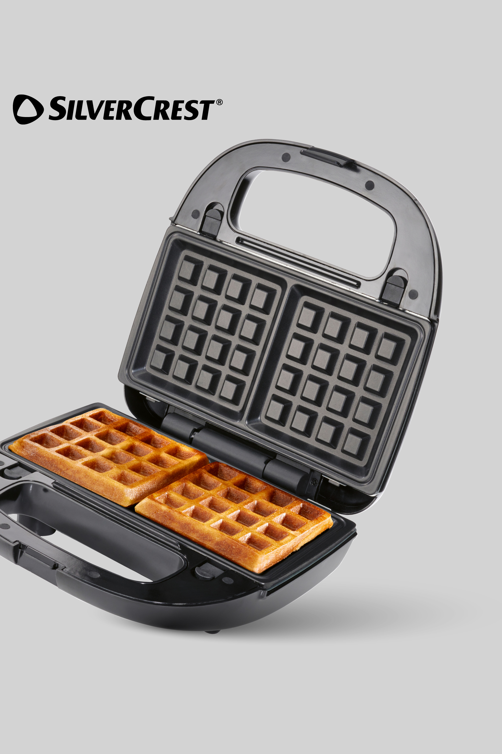 Odpirač za vaflje z dvema zlato rjavima vafljema in prazno zgornjo ploščo.