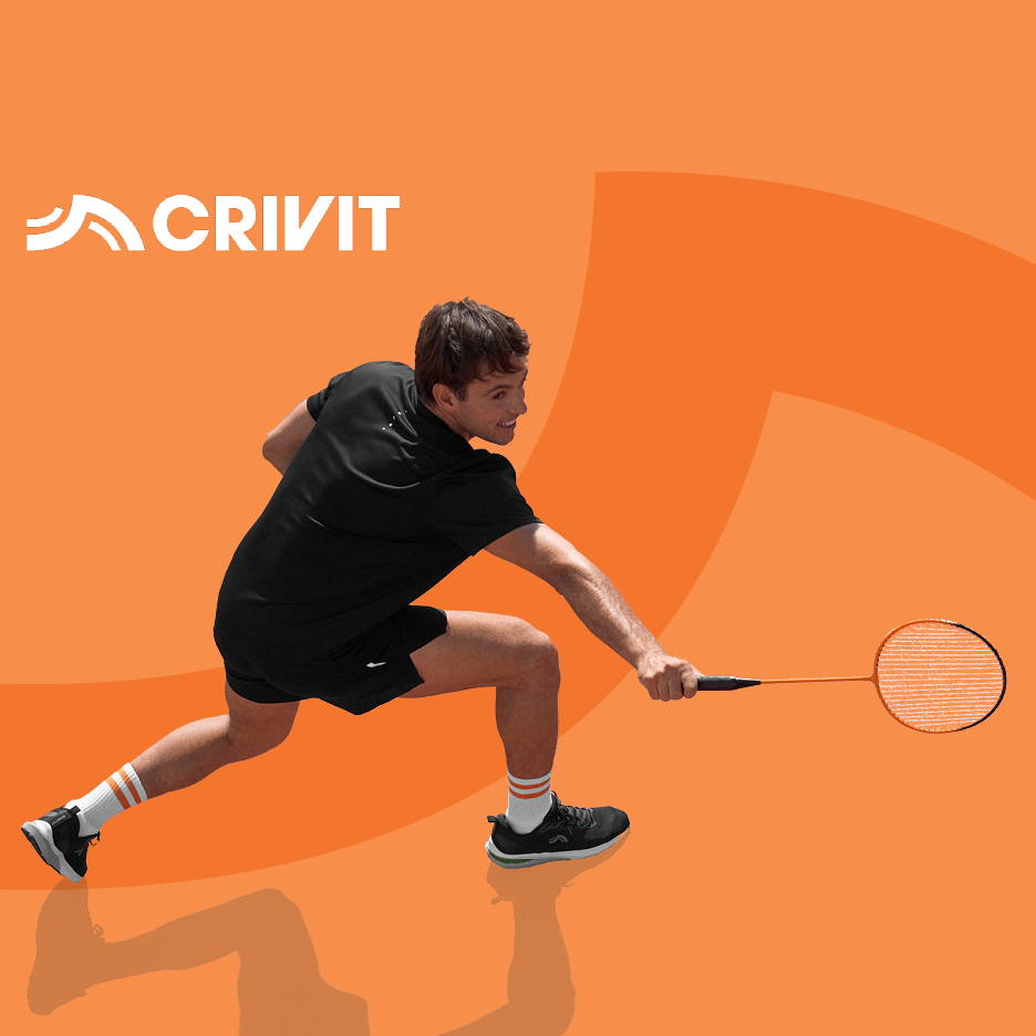 Moški v črni športni opremi igra badminton z oranžnim loparjem.